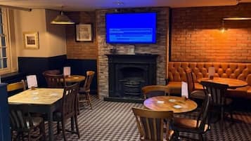 A cozy dining area with a brick wall, a fireplace, and a television screen.