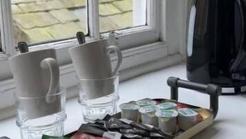 A tray with coffee cups and tea packets on a windowsill.