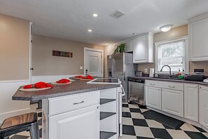 A kitchen with white cabinets, a granite countertop, a stainless steel refrigerator, and a black and white checkered floor. - Historic 1851 Downtown Elizabethtown Home (Elizabethtown)