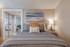 A bedroom with a bed, a nightstand, a lamp, a painting, and a view of a hallway. - Historic 1851 Downtown Elizabethtown Home (Elizabethtown)