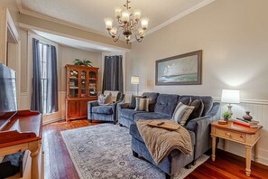 A living room with a sofa, armchairs, a wooden cabinet, a chandelier, and a painting on the wall. - Historic 1851 Downtown Elizabethtown Home (Elizabethtown)