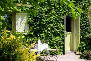 A garden with a table and chairs, a door, and a wall covered in green foliage. - Guest Room 'Chambre À L'étage' with Lake View and Wi-Fi (Chamborand)