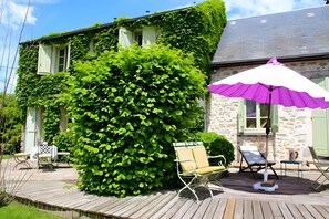 A house with ivy-covered walls, a wooden deck, and outdoor seating.