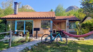 A wooden house with a tiled roof, a hammock, and a bicycle.