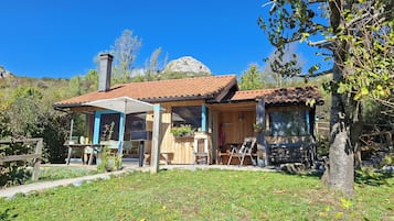Uma cabana de madeira com telhado de cerâmica, alpendre coberto e lareira de pedra.