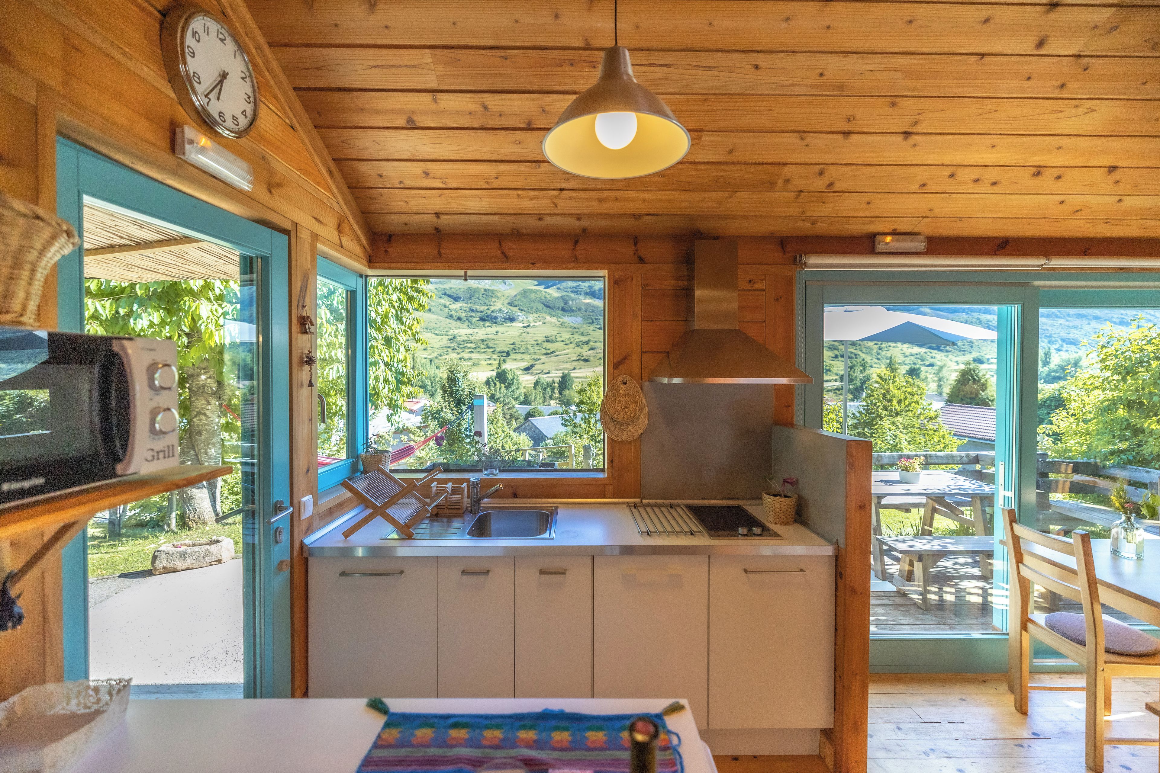 Un interior de madera con cocina, una mesa de comedor y vistas al exterior.