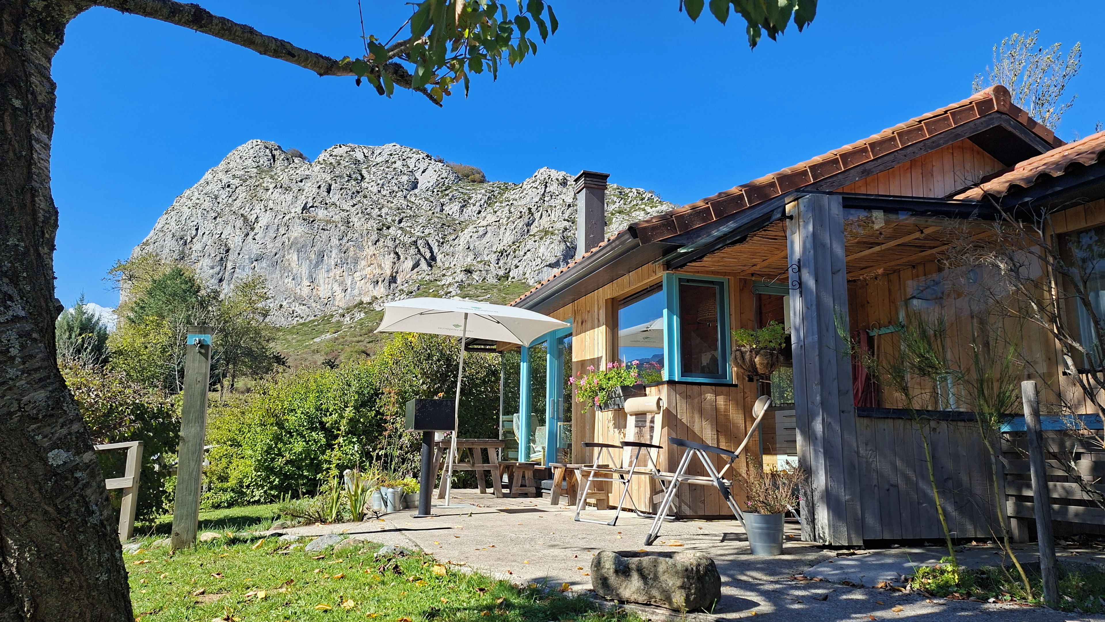Une cabane en bois avec un patio, un paysage de montagne en toile de fond et un ciel dégagé.