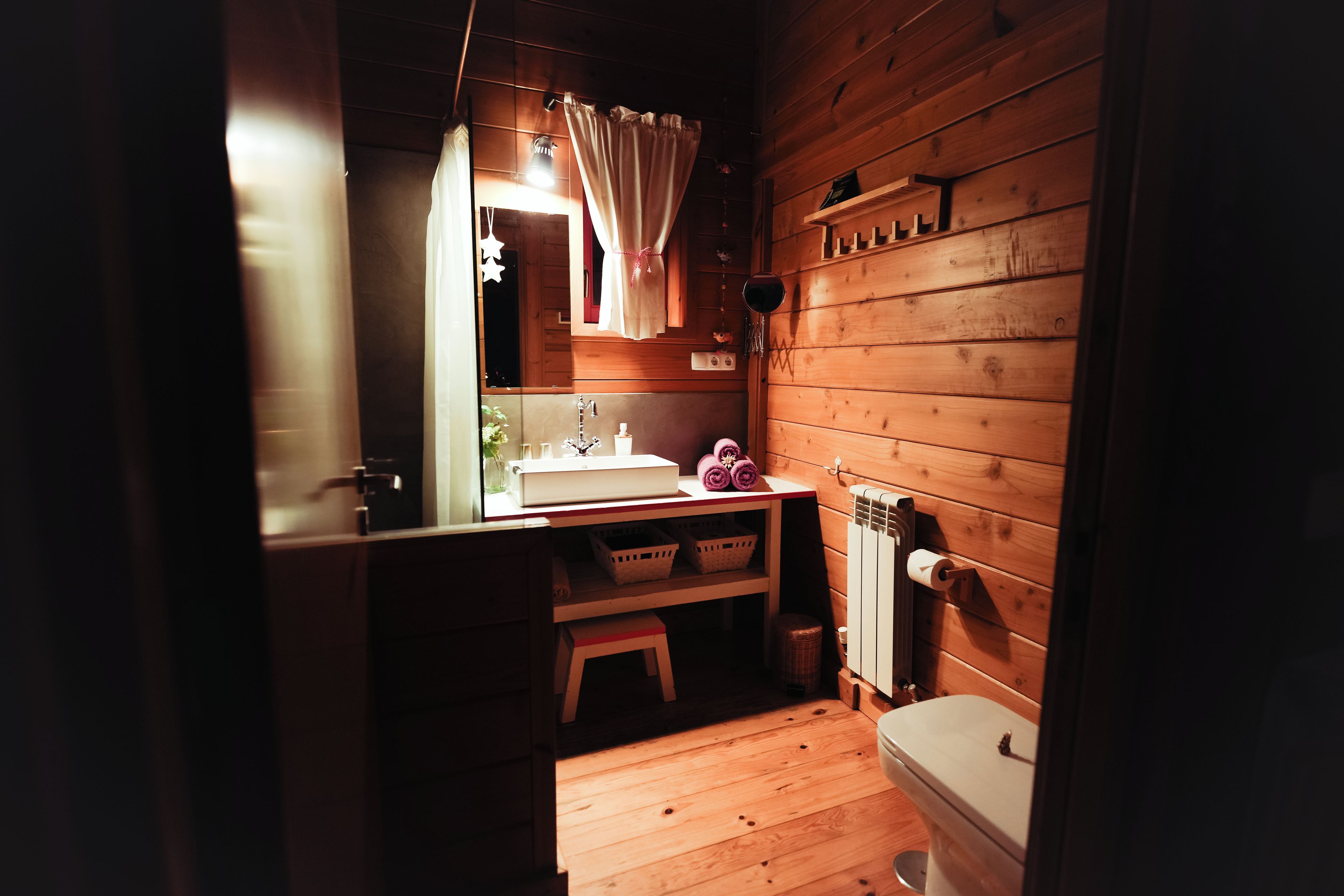 Un baño pequeño de madera con lavamanos, espejo y retrete.