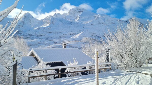 A snow-covered mountain landscape with a house and a wooden fence.