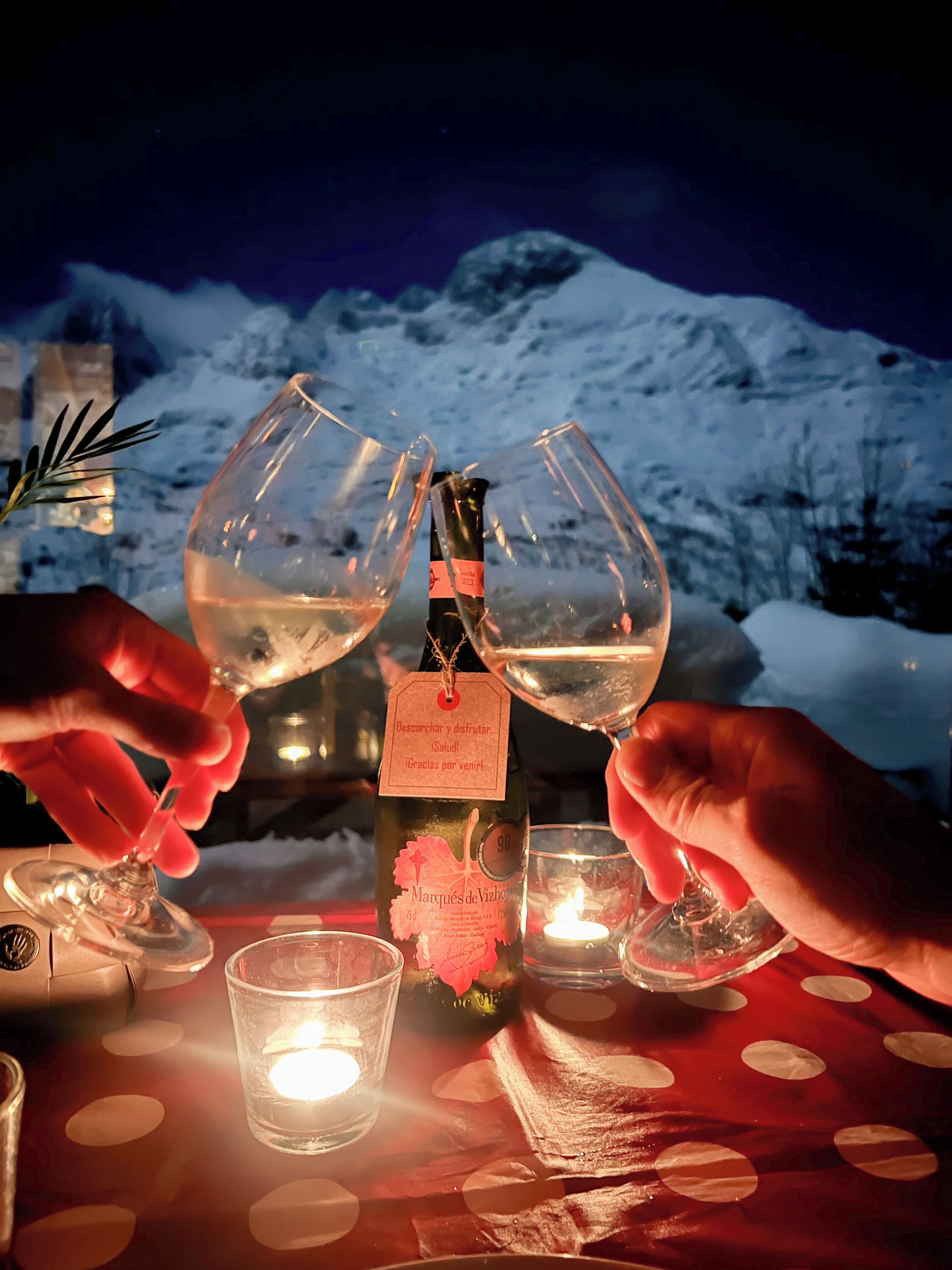 Un tavolo con una bottiglia di vino, due bicchieri da vino e una candela.