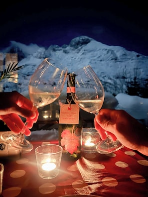 A table with a bottle of wine, two wine glasses, and a candle. - Cabañas Patagónicas (Maraña)