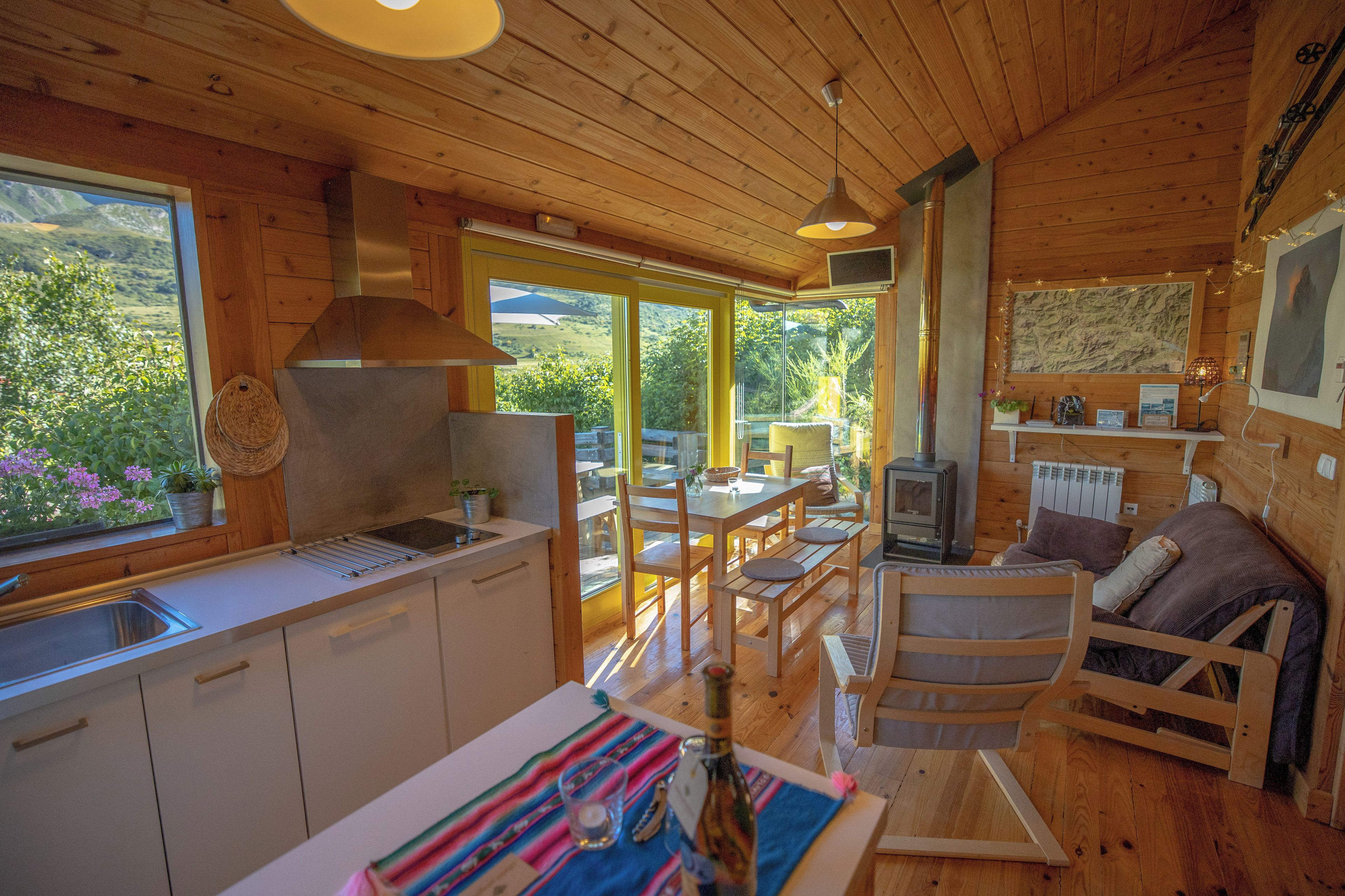 A wooden cabin interior with a kitchen, dining area, and a cozy seating area.