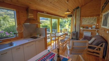 A wooden cabin interior with a kitchen, dining area, and a cozy seating area.