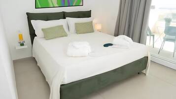 A modern hotel room with a large bed, a view of the outdoors, and a painting on the wall.