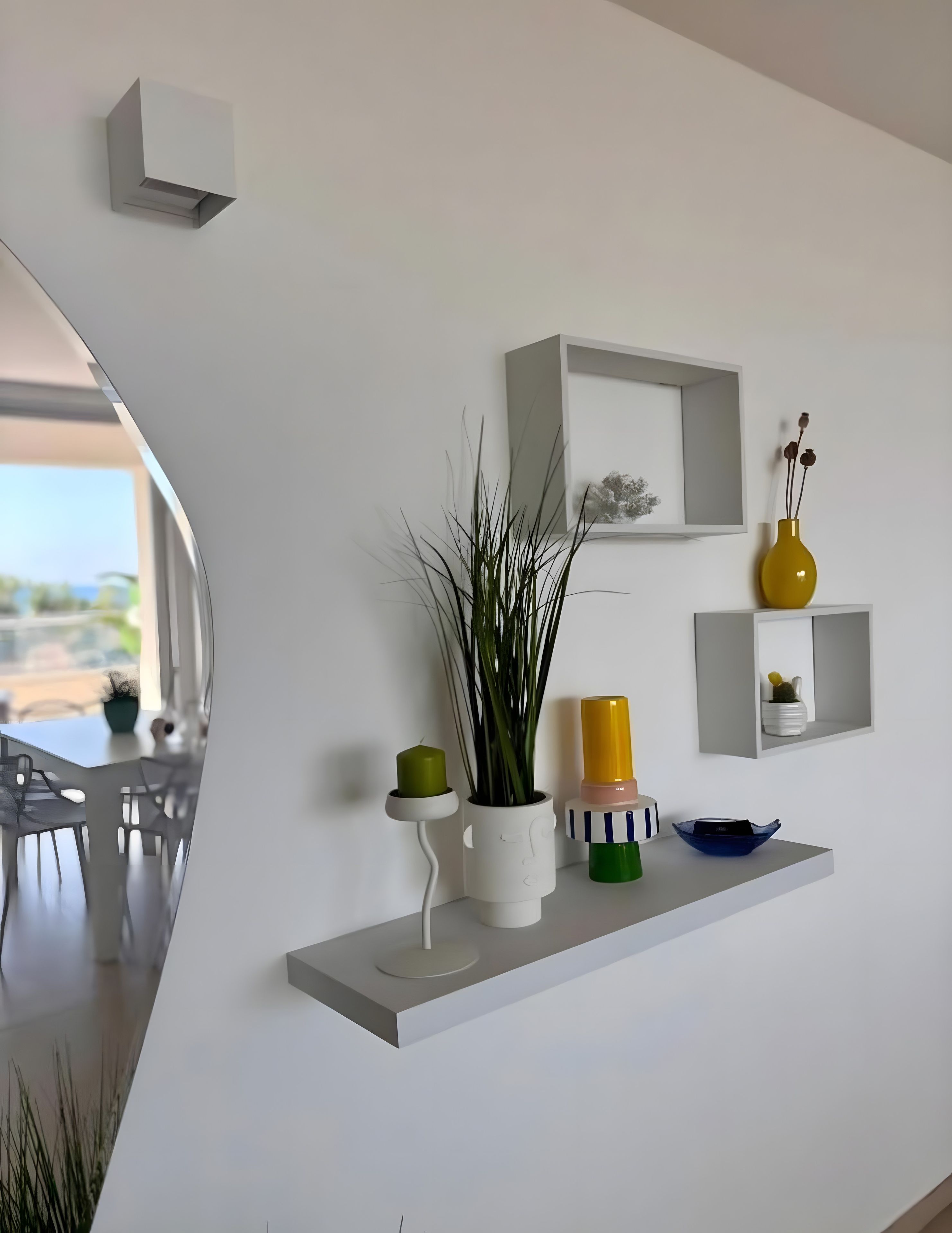 Een modern interieur met witte muren, een eethoek met een tafel en stoelen, en planken met decoratieve accessoires.