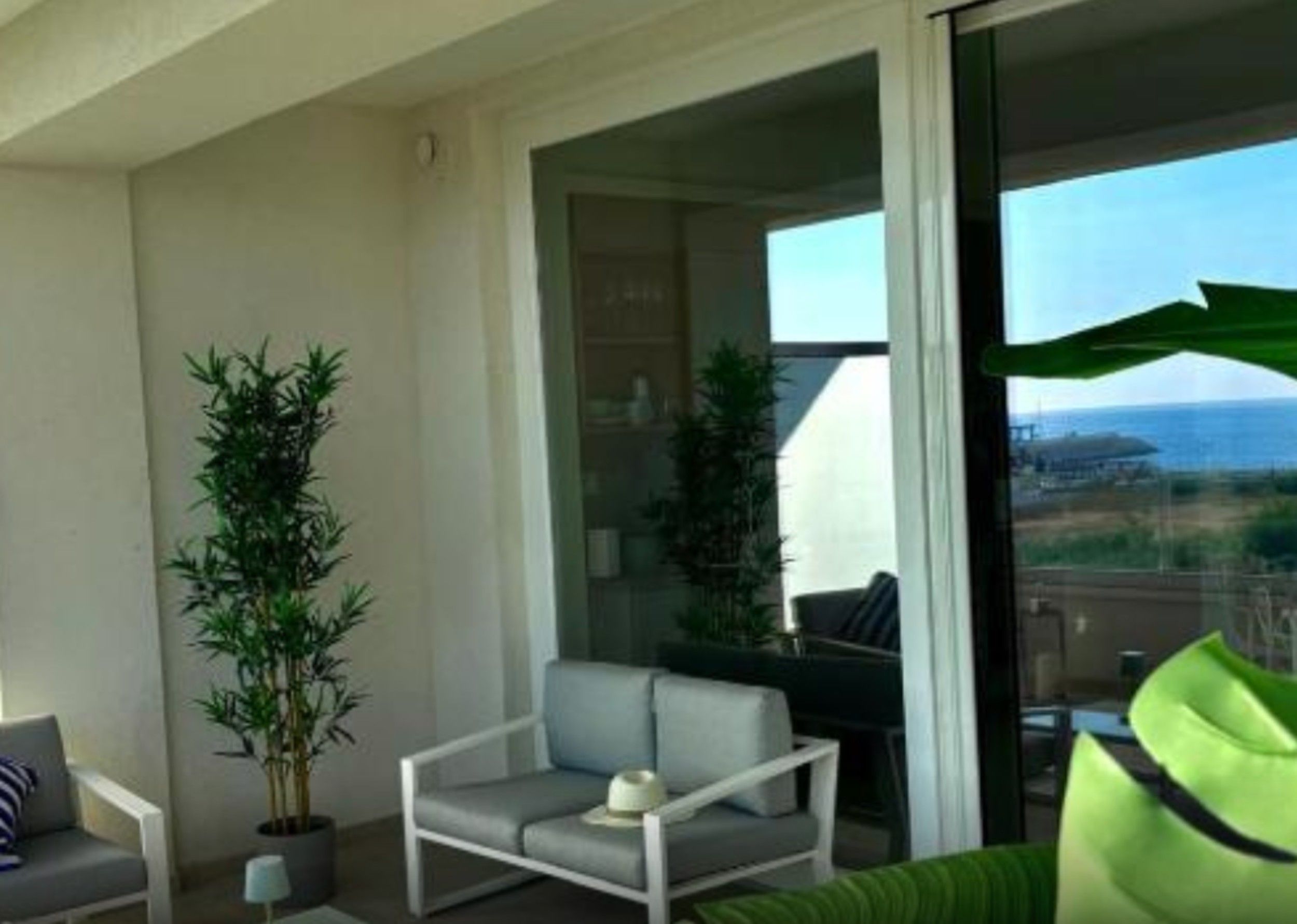 Ein Balkon mit einer Couch, einem Sessel und zwei Blumentöpfen.