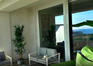 Ein Balkon mit einer Couch, einem Sessel und zwei Blumentöpfen.
