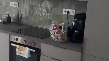 Uma cozinha com forno embutido, pia e máquina de café.