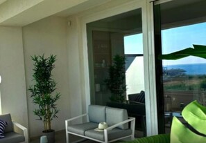 Ein Balkon mit einer Couch, einem Sessel und einem Blumentopf.