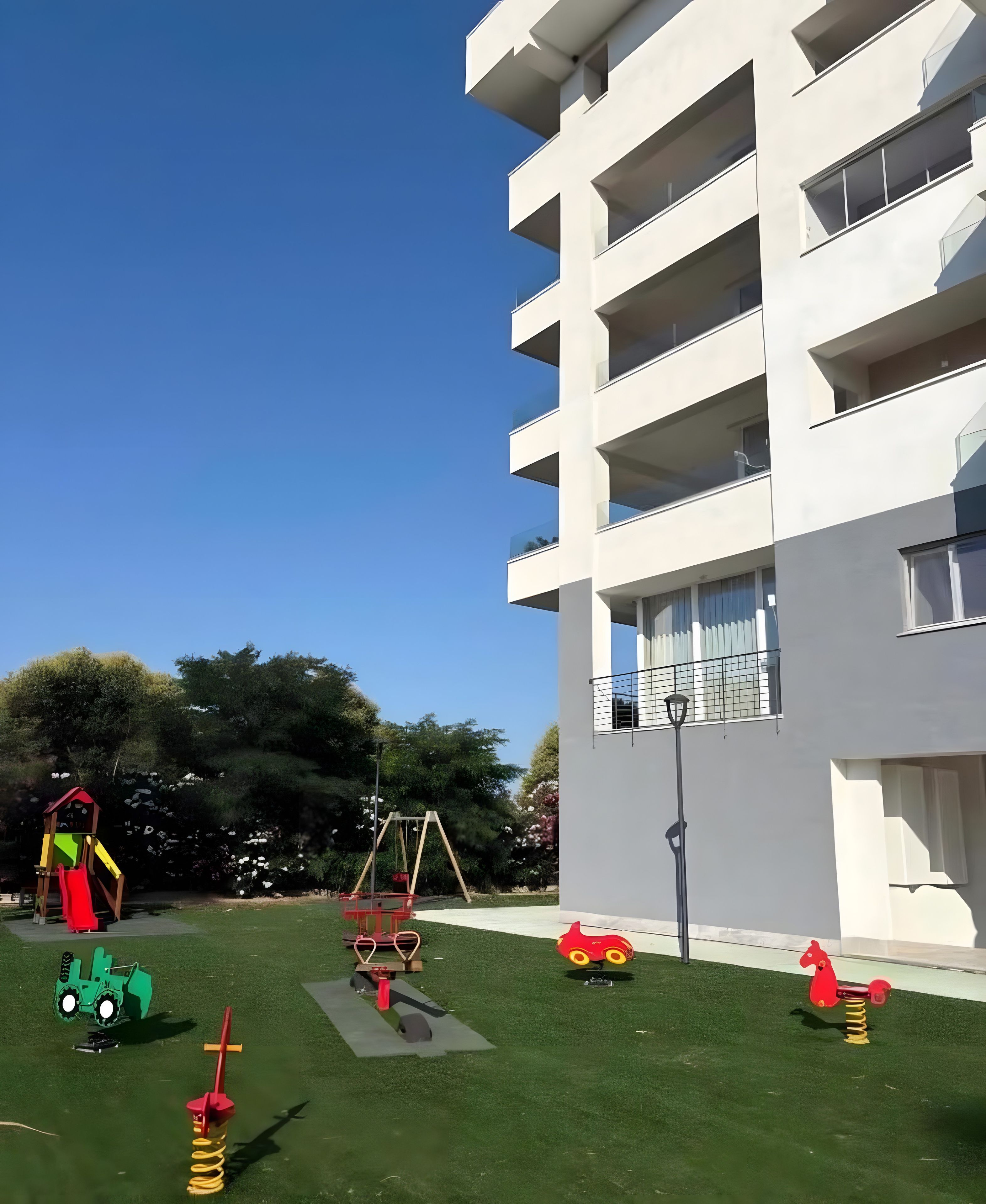 Un’area giochi con diverse strutture ricreative, un prato verde e un edificio moderno con balconi.