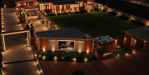 A resort with a well-lit outdoor area, a pool, and a sign indicating amenities like party lawn and banquet.