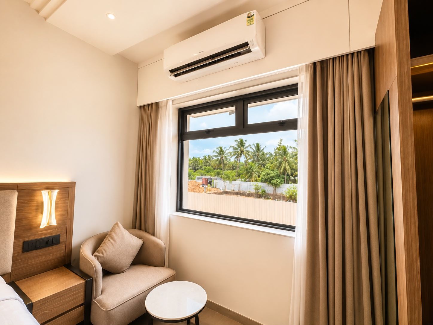 Habitación de hotel con sofá, una mesita, aire acondicionado y ventana con cortinas.