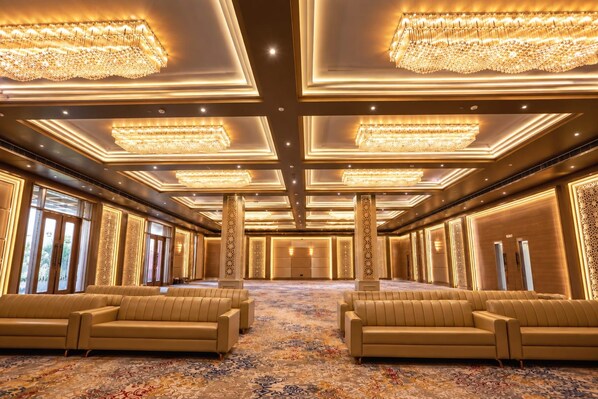 A spacious hotel lobby with high ceilings, ornate chandeliers, and plush seating areas.
