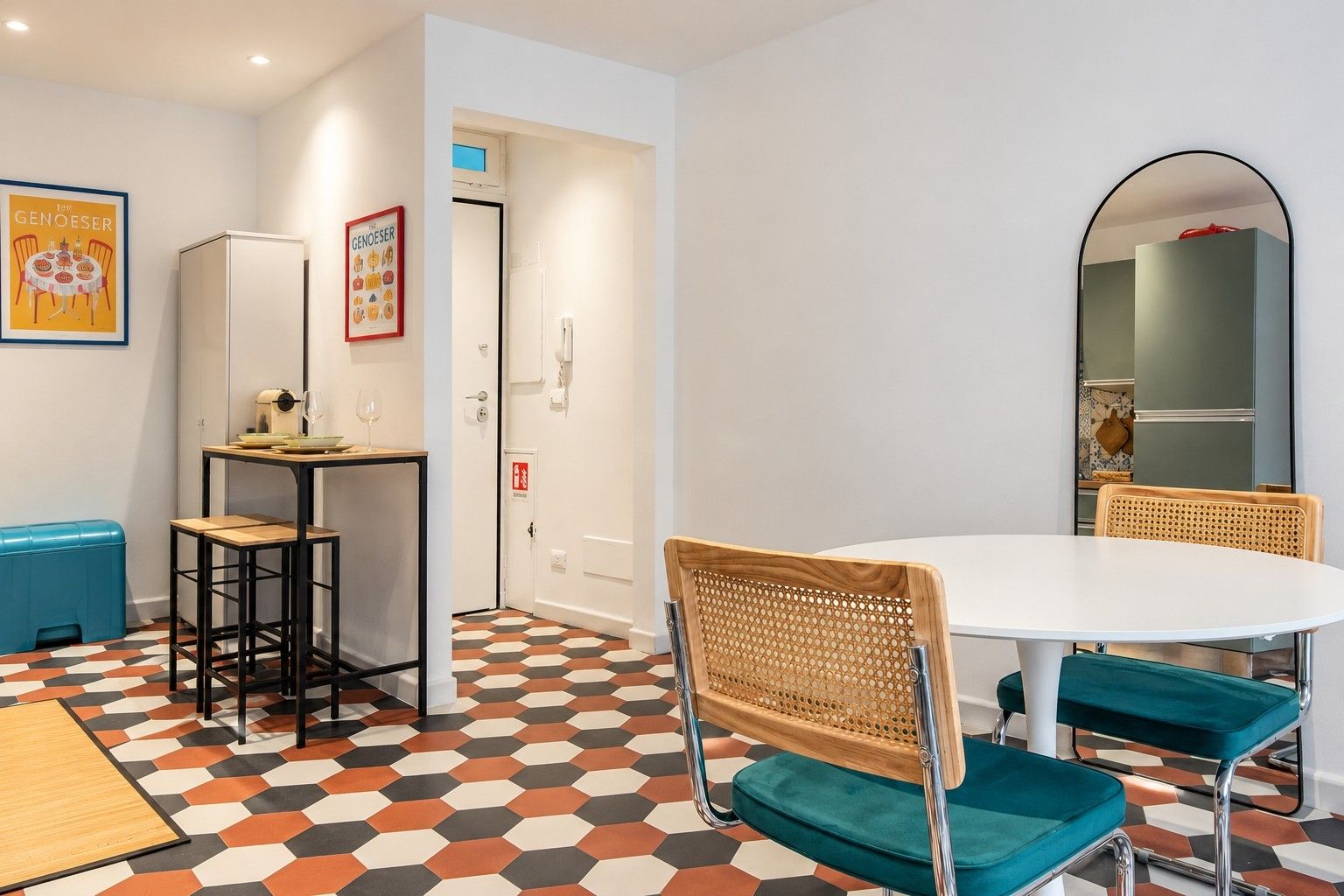 Una stanza moderna con un tavolo rotondo, due sedie, un piccolo angolo bar e un pavimento decorato.