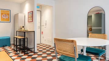 Una stanza moderna con un tavolo rotondo, due sedie, un piccolo angolo bar e un pavimento decorato.