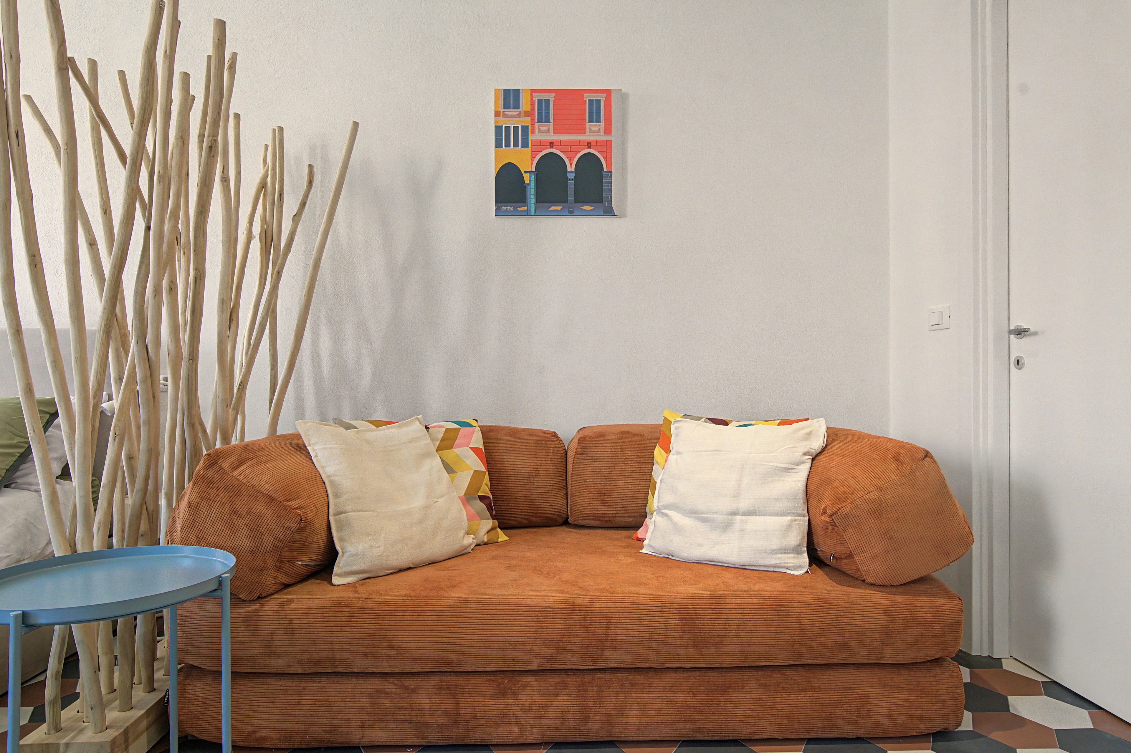 Ein Zimmer mit einem braunen Sofa, einem kleinen Tisch und einer Wand mit einem gerahmten Bild.