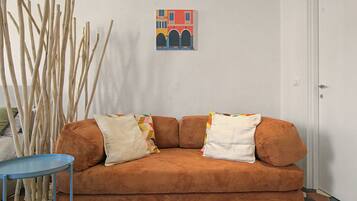 Ein Zimmer mit einem braunen Sofa, einem kleinen Tisch und einer Wand mit einem gerahmten Bild.