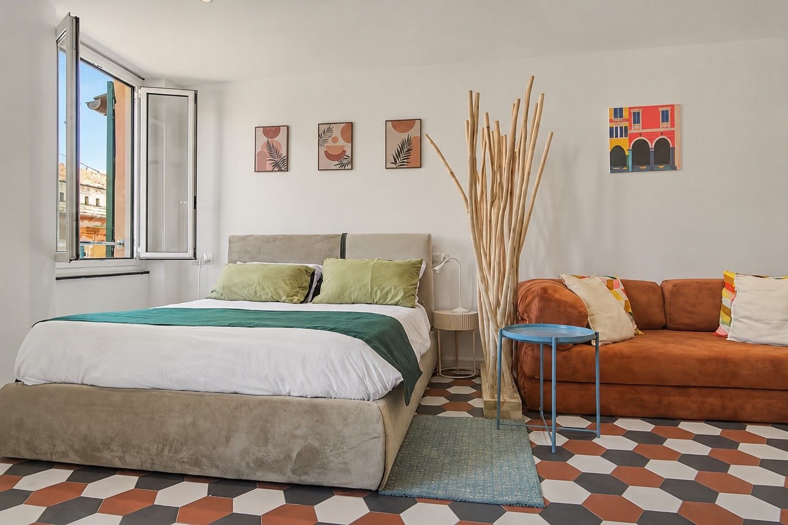 Ein Schlafzimmer mit einem Bett, einer Schlafcouch, einem Fenster und Bildern an der Wand.