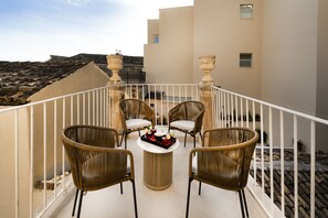 Een terras met rieten stoelen, een ronde tafel en een dienblad met drankjes.