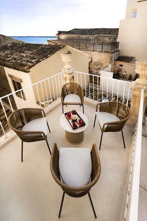 A terrace with wicker chairs and a table, overlooking a coastal view. - Dimora Italia Blu Calypso Ortigia (Ortigia)