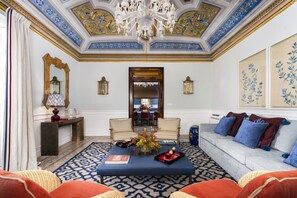 A luxurious room with a chandelier, ornate ceiling, and a sofa with decorative pillows. - Dimora Italia Blu Calypso Ortigia (Ortigia)