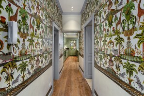 A hallway with patterned wallpaper and wooden flooring, leading to a kitchen area. - Dimora Italia Bianca Arethusa Ortigia (Ortigia)
