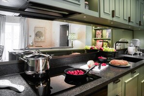 A modern kitchen with a stove, pots, a bowl of tomatoes, and a loaf of bread on the counter. - Dimora Italia Bianca Arethusa Ortigia (Ortigia)