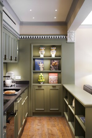 A kitchen with a built-in bookshelf, a coffee machine, and a loaf of bread on the counter. - Dimora Italia Bianca Arethusa Ortigia (Ortigia)