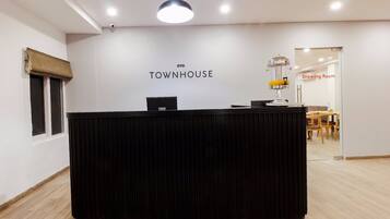Uma receção com uma placa a indicar 'OYO TOWNHOUSE' num interior moderno, com uma área de refeições visível ao fundo.