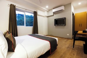 Habitación de hotel con cama, escritorio, televisor y aire acondicionado.