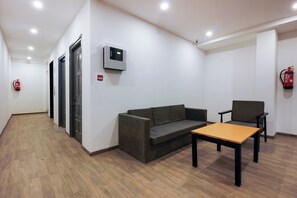 Habitación con sofá, una mesita, extintor y detector de incendios en la pared.