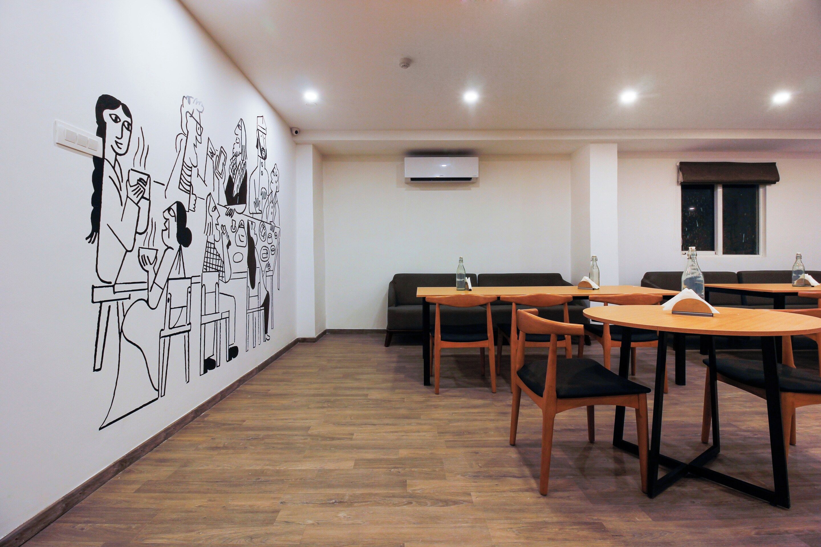 A dining area with wooden tables and chairs, a wall mural, and an air conditioning unit.