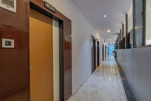 Un couloir d’hôtel avec une porte en bois portant le numéro « 301 » et un sol en marbre.