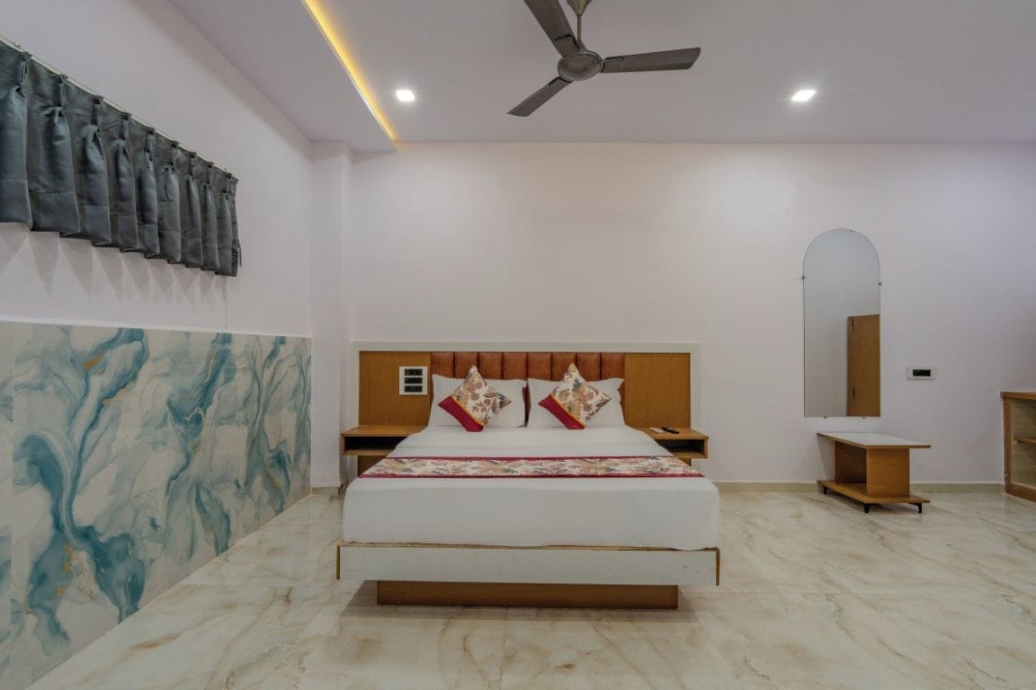 A bedroom with a bed, nightstands, a ceiling fan, a mirror, and a marble wall.