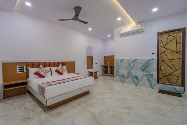 Une chambre à coucher comprenant un lit, des tables de chevet, un ventilateur de plafond, un appareil de climatisation, un sol en marbre et un panneau décoratif mural.