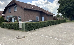 Ein zweistöckiges Backsteinhäuschen mit Ziegeldach und einer überdachten Veranda, sowie einem gepflasterten Auffahrt.