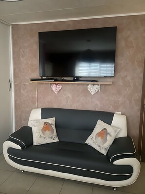 Ett modernt vardagsrum med en svartvit soffa, en väggmonterad platt-TV och dekorativ väggkonst.