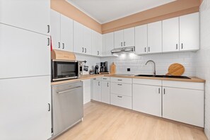 A modern kitchen with white cabinets, stainless steel appliances, and a wooden countertop. - Sea-view Stay With Garage (Blankenberge)