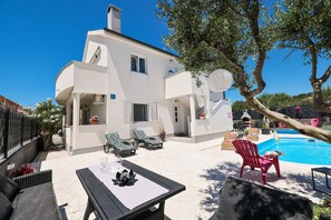 A modern villa with a swimming pool, outdoor seating, and a tree providing shade. - Villa Feliks Zadarvillas (Razanac)