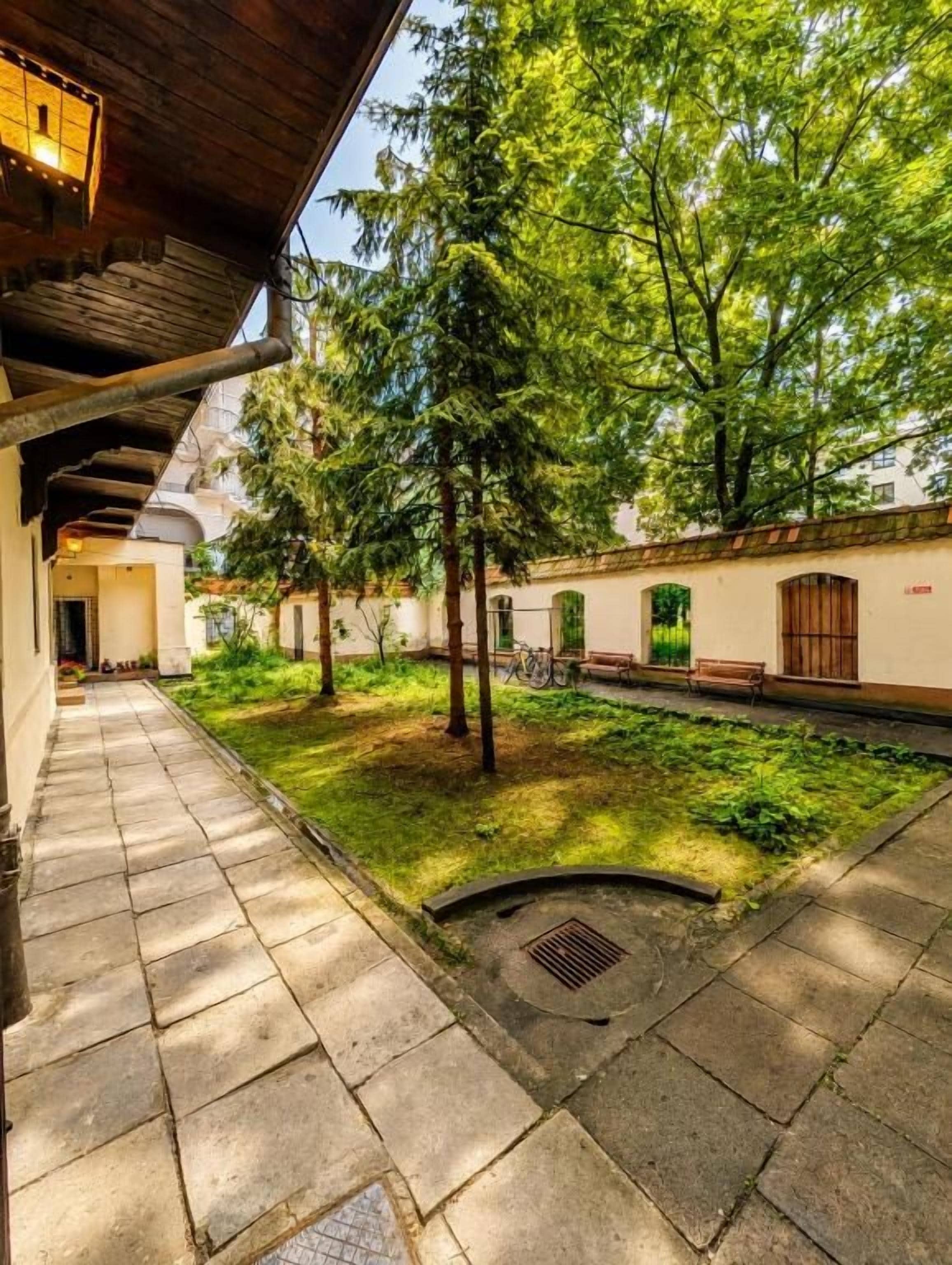Un patio con un camino de piedra, árboles y un edificio con techo de madera.